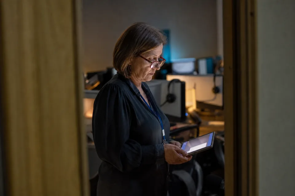 Support manager checking a tablet with a new review alert during an evening shift in a support room